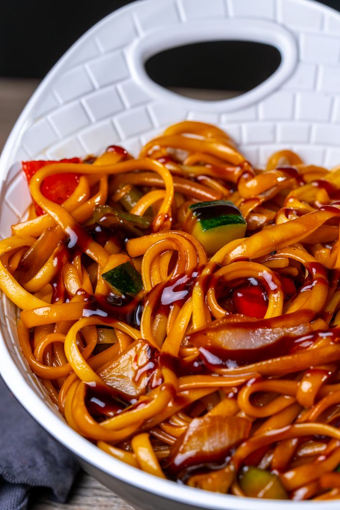 Appetizing stir-fried noodles with vegetables in a white bowl, perfect for Asian cuisine lovers.